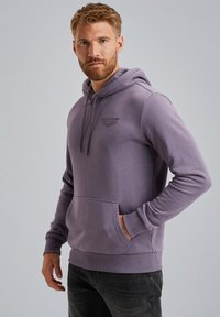 Paarse hoodie gemaakt van zachte stof, met een kangoeroezak, capuchon met trekkoord en geribde manchetten. Subtiele logo op de borst.