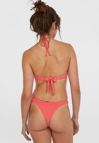 Koraal bikini-set met een haltertop met strik achter en hoog uitgesneden onderkant, gemaakt van gladde stof in een effen kleur met minimale details.