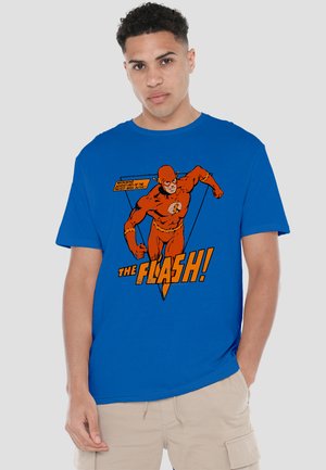 Young man wearing a blue t-shirt with vintage comic-style Flash superhero running and text "The Flash!" in orange.