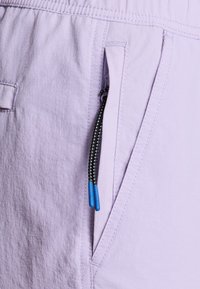 Világos levendula színű, textúrált felszínű shorts, oldalsó zsebből és fekete, kék végű húzókából áll. Egyszerű dizájn, elasztikus derékpánt.