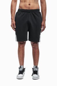 Schwarze Sportshorts mit elastischem Bund, weißen Seitenstreifen und kontrastierenden Nähten, kombiniert mit High-Top-Sneakern.