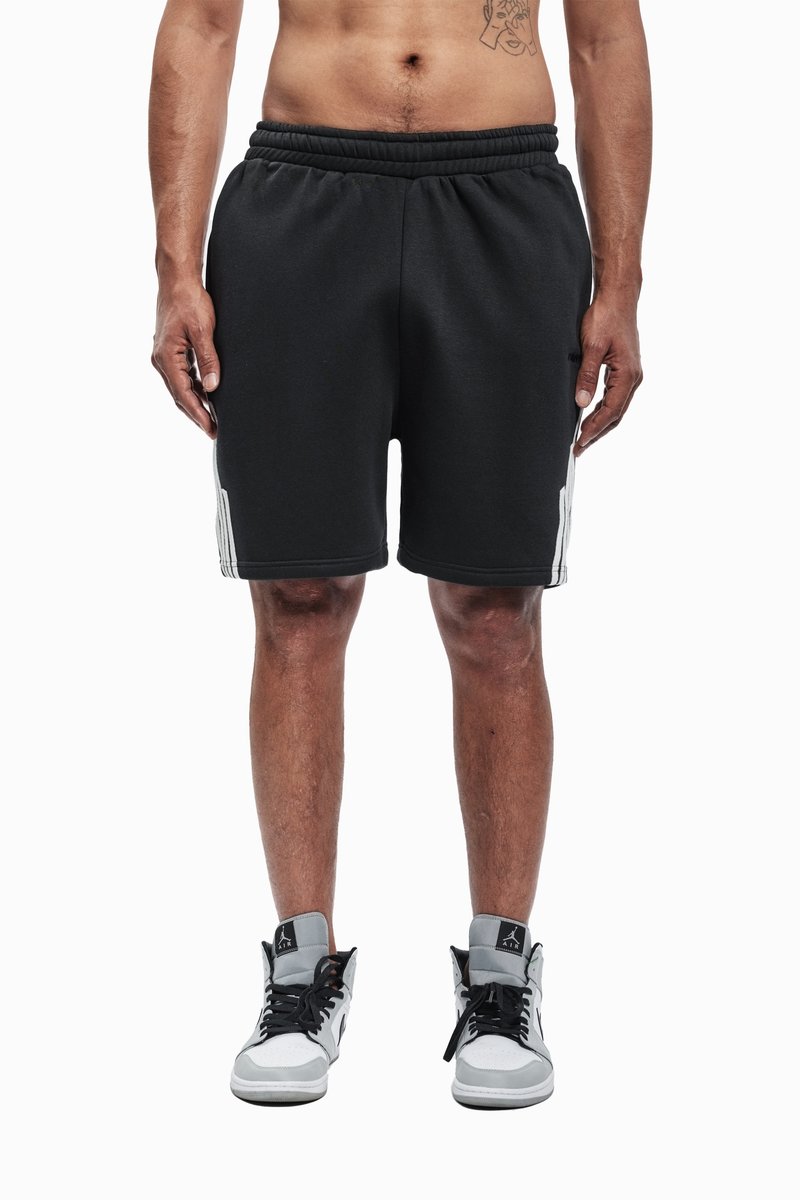 Schwarze Sportshorts mit elastischem Bund, weißen Seitenstreifen und kontrastierenden Nähten, kombiniert mit High-Top-Sneakern.