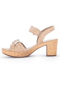 Beżowe zamszowe sandały z dwoma regulowanymi paskami na kostkę, plecionym przodem i grubym korkowym obcasem dla większej stabilności.