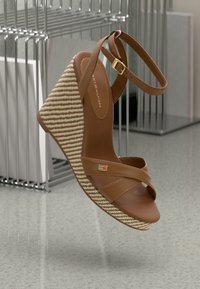 Sandale à talon en bois marron avec semelle tissée beige, bride de cheville avec boucle dorée, et logo Tommy Hilfiger sur la bride et la semelle intérieure.
