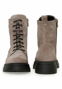 Gray suede ankle boots with black laces, side zipper, and a chunky black rubber sole. Features a smooth texture and minimal accents.