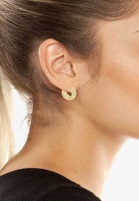 Gold-tone hoop earrings with a textured surface, featuring a crescent shape and a small closing mechanism.