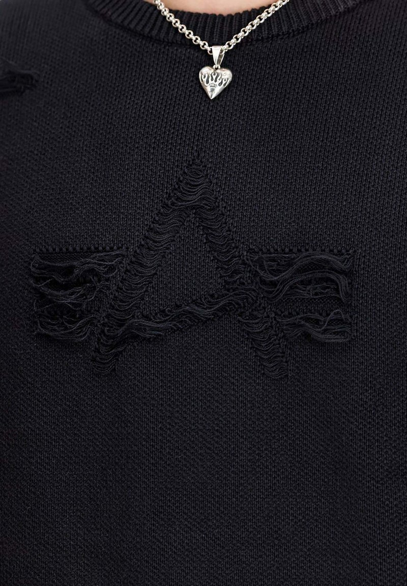 Schwarzer Strickpullover mit einem distressed Grafik "EA" auf der Vorderseite, mit Rundhals und begleitet von einer silbernen Herzanhängerkette.