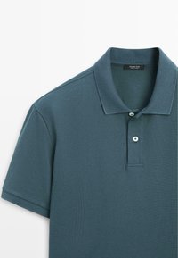 Polo bleu à manches courtes avec deux boutons et un col classique, fabriqué en tissu texturé.