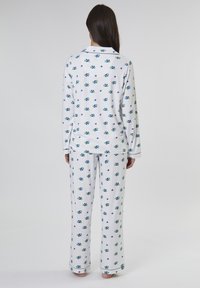 Weißer Schlafanzug mit blauem und grünem Blumenmuster, langärmliges Oberteil und lockere Hose, aus weichem Stoff mit kontrastierenden Bündchen.