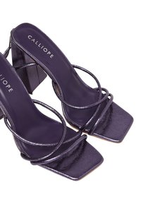 Sandali alti viola con punta quadrata, dotati di cinturini metallici e tacco chunky. Texture liscia con logo sulla soletta.