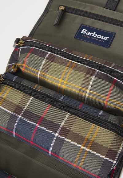 Intérieur d'un sac à dos Barbour montrant un tissu vert olive avec deux compartiments à carreaux zippés dans des tons de vert, bleu marine, rouge, blanc et jaune.