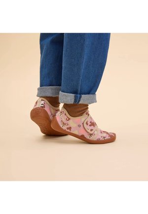 Chaussures en tissu rose avec imprimé animal, accents beige et sangles Velcro. Semelle en caoutchouc avec motif texturé. Portées avec un jean bleu retroussé.