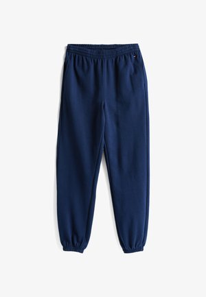 Pantalones de chándal azul marino hechos de tela suave, con cinturilla elástica y piernas estrechas con puños elásticos. Sin patrones ni acentos adicionales.