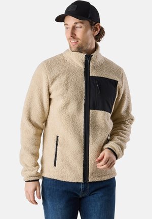 Beige fleece jacket with a high collar, black zippered chest pocket, and side pockets. Textured fabric and fitted cuffs.