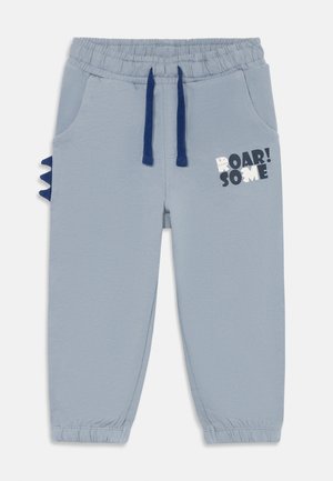 Hellblaue Kleinkinderhose mit elastischem Bund, marineblauen Kordeln, seitlichen Dinosaurierstacheln und der Aufschrift „ROAR! SOME“ am rechten Oberschenkel.