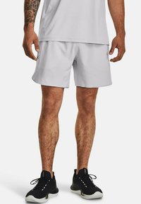 Hellgraue Sportshorts mit einem elastischen Bund und seitlichen Taschen, kombiniert mit schwarzen Sneakers mit einer strukturierten Sohle und Schnürsenkeln.