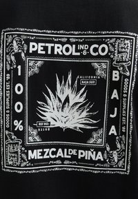 Tessuto nero con motivo grafico bianco raffigurante una pianta di agave, testo "PETROL IND. CO", "100% MEZCAL DE PIÑA" e bordi decorativi.