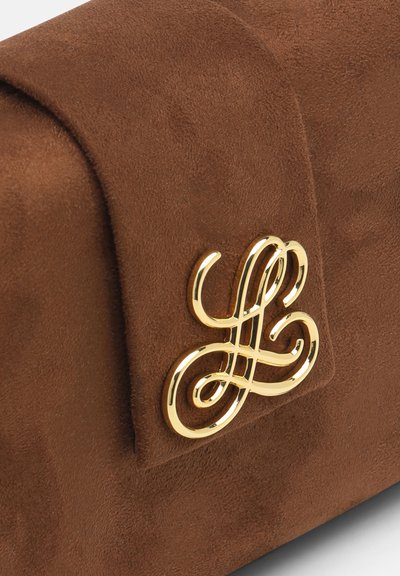 Brun ruskindstaske med en gylden, udsmykket sammenflettet monogramlås i kursiv på frontklappen.