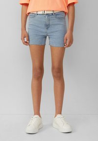 Jasnoniebieskie szorty dżinsowe z postrzępionym dołem, z pięcioma kieszeniami i białym paskiem. Połączone z białymi trampkami dla uzyskania swobodnego wyglądu.