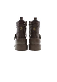 Botas de tobillo de cuero marrón con diseño acolchado, cremalleras traseras y correa decorativa. Presentan un logo en relieve y acentos texturizados en los laterales.