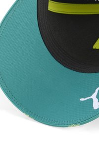 Teal kasket med en struktureret overflade; skyggen er sort med en neongrøn stribe og et hvidt logo på siden. Cirkelstikdetalje synlig.