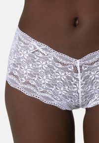 Witte kant boyshorts met bloemenpatronen, voorzien van ingewikkelde randen en een centraal strikje op de tailleband. Zachte, textuurrijke stof.
