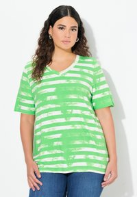 Camiseta de cuello en V a rayas verdes y blancas con mangas cortas, hecha de una tela suave, que presenta un corte holgado y un patrón desgastado.