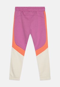 Lila sweatpants med orange och krämfärgade accenter. Har resårmidja och åtsittande muddar vid anklarna. Mjuk textur.