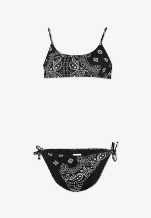 Bikini nero a due pezzi con motivo paisley e floreale bianco, composto da un top a bralette con spalline sottili e slip con laccetti ai lati.