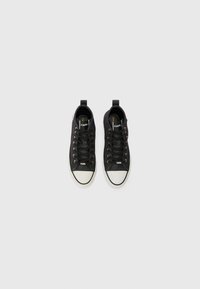 Sneaker nere in canvas con punta in gomma bianca e occhielli dorati, dotate di lacci e linguette sul tallone per indossarle facilmente.