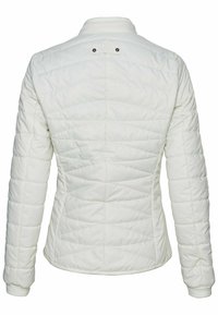 Veste blanche matelassée à manches longues avec col montant, coutures visibles et petite patte avec deux boutons noirs au haut du dos.