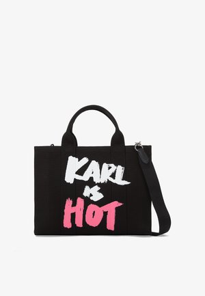Zwarte canvas draagtas met dubbele handvatten en een afneembare schouderband. Kenmerkt een gedurfde tekst "KARL is HOT" in witte en roze verfachtige letters.