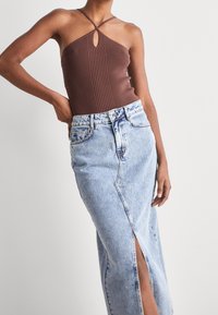 Hnědý žebrovaný top na ramínka s detaily ve tvaru klíčové dírky, kombinovaný s světle modrou džínovou sukní se spodničkou a vysokým pasem.