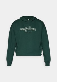 Felpa corta verde realizzata in tessuto morbido, con il testo "GOING SOMEWHERE New" in bianco. Include un cappuccio con coulisse e polsini a costine.