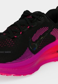 Μαύρο και φωτεινό ροζ αθλητικό παπούτσι Nike με μαύρα κορδόνια, ροζ λωρίδες σε κυματιστό σχέδιο και μαύρο λογότυπο Nike στο πλάι.