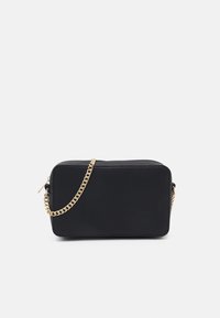 Borsa a tracolla nera in pelle guilloche rettangolare con tracolla in catena dorata e chiusura con cerniera su uno sfondo bianco.
