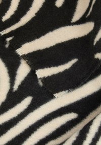 Tessuto a strisce zebrate in bianco e nero con una consistenza morbida. I bordi sono sfilacciati, creando un effetto grezzo. Il motivo presenta strisce alte e alternate.