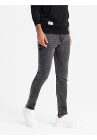 Jeans gris de corte slim hechos de denim. Presentan una textura suave con un lavado desgastado, diseño de cinco bolsillos y detalles de costura a lo largo de las piernas.