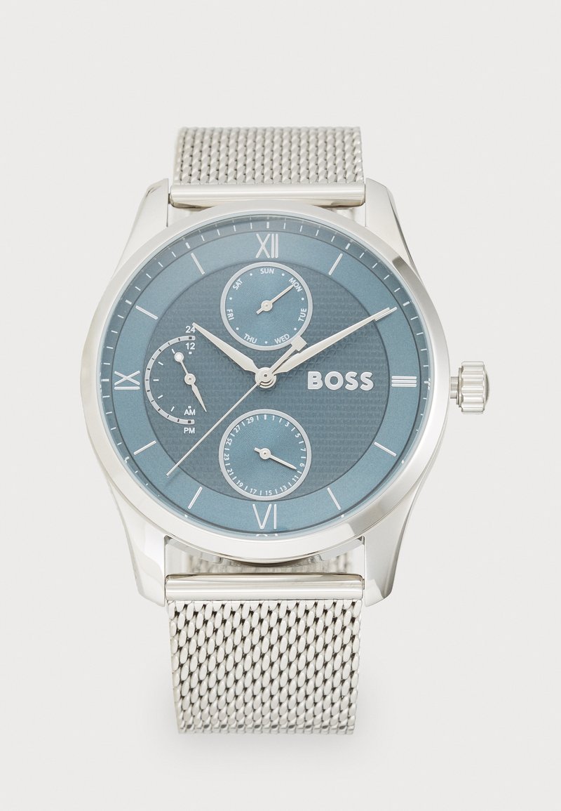 Reloj de malla plateada con una esfera redonda azul, números romanos, tres subesferas y una superficie texturizada. Nombre de la marca "BOSS" mostrado de forma prominente.