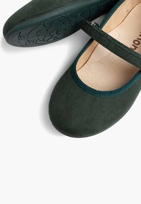 Bailarinas de ante verde oscuro con correa al estilo Mary Jane, ribete verde en contraste y suela de goma texturizada con un patrón floral.