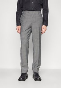Grau gemusterte Anzughose mit schmalem Schnitt, flachem Frontbereich, Seitentaschen und Gürtelschlaufen, kombiniert mit schwarzen Schuhen. Glatte Textur.