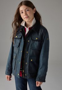 Mørkeblå, let jakke med en fløjlsagtig krave, guldfarvet hardware, flere forlommer og lynlåslukning foran.