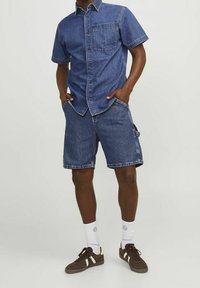 Denim-paita lyhyillä hihoilla, etutasku; yhdistetty polvenpituisiin denim-shortsihin. Molemmat tummansiniset, rento malli, näkyvillä ompeluilla.