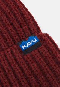 Bordeaux strikket lue med en blå og svart KAVU-logo-patch. Teksturen er tykk og ribbet med et mykt, fluffy utseende.