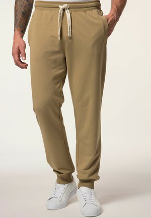 Khaki-Sweatpants mit elastischem Bund, verstellbarem Kordelzug, Seitentaschen und gerippten Bündchen, kombiniert mit weißen Sneakern.