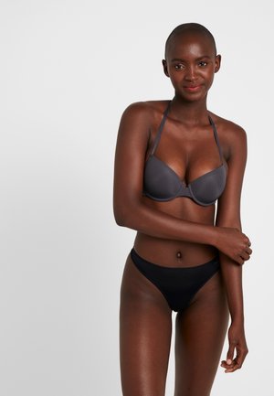 Grijze gewatteerde beha met verstelbare bandjes en een zwarte bikinionder. Gladde stof met minimale hardware. Eenvoudig, ergonomisch ontwerp.