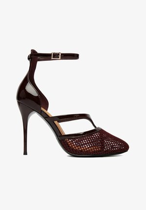 Tacón de aguja burdeos oscuro con correa en el tobillo, cuerpo de cuero charol brillante y diseño de punta puntiaguda de malla tejida.
