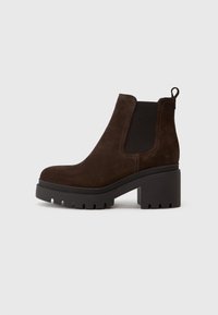 Bottines en suède marron avec des panneaux élastiques sur les côtés et une languette, dotées d'un talon bloc et d'une semelle crantée pour l'adhérence.