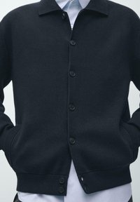 Marineblauer Cardigan aus strukturiertem Strickstoff, mit einem Kragen, Knöpfen vorne und zwei Seitentaschen.