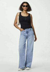 Mustat tiiviit tank topit, joissa on nappidetaileja, yhdistettynä vaaleansinihin leveälahkeisiin farkkuihin ja valkoisiin lenkkareihin; asusteina kevyet laukku ja aurinkolasit.